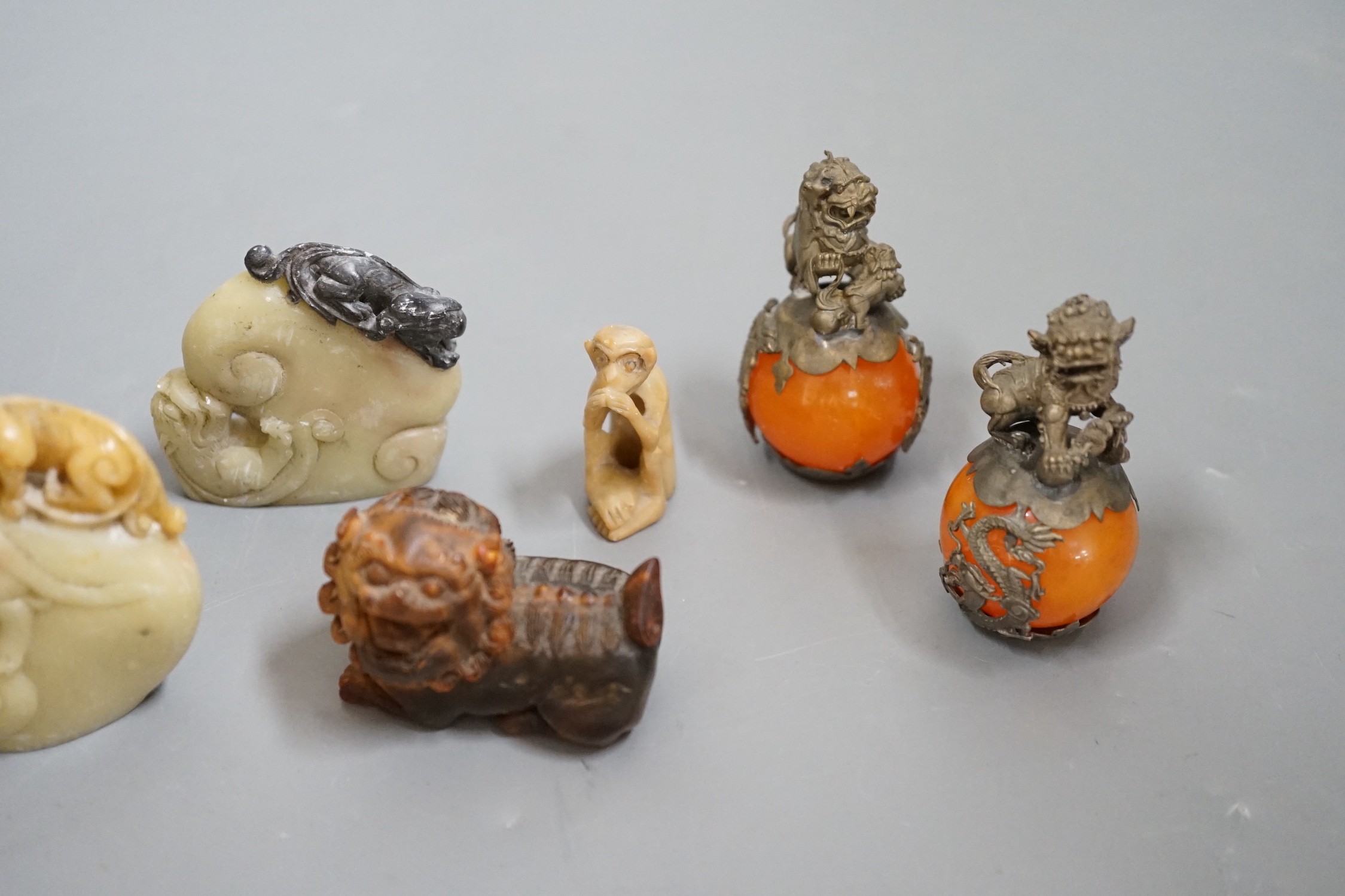 Two carved horn Buddhistic lions, four soapstone carvings and a pair of Chinese nickel and amber-glass ornaments, horn lions 5cm wide